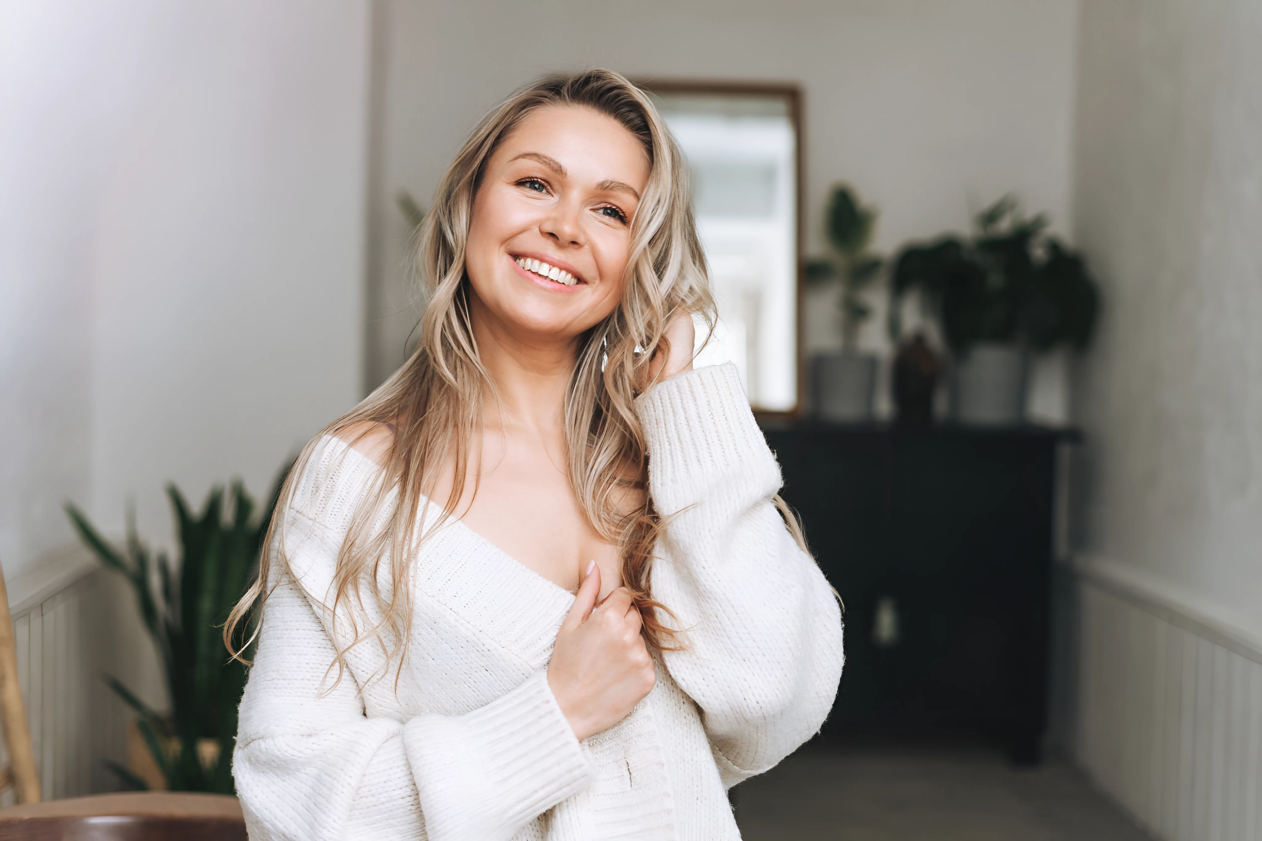 Smiling woman in a white sweater in a bright hallway